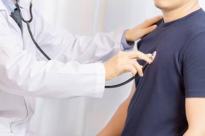 Profissional de saúde auscultando o peito de um paciente com estetoscópio, em uma consulta cardiológica