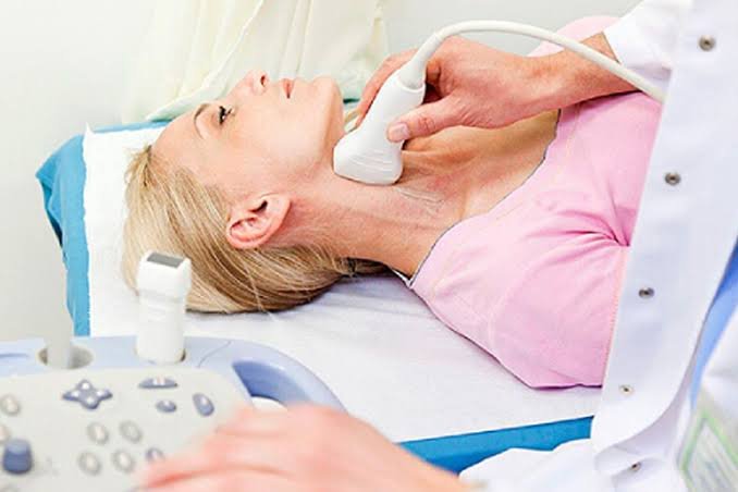 Mulher deitada com o transdutor do ultrassom no pescoço, durante o Doppler de carótidas e vertebrais